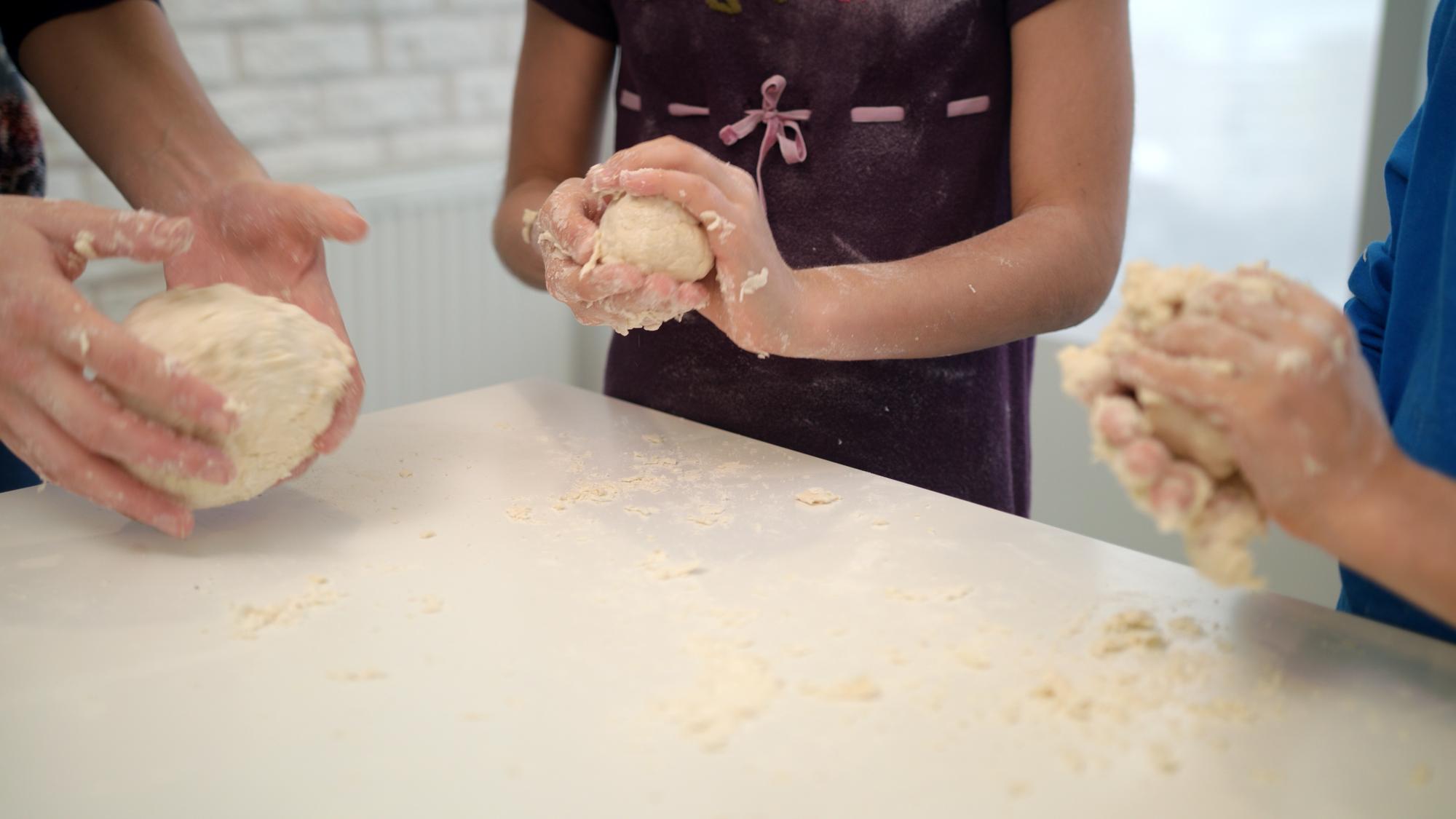 Chef and participant shaping dough together